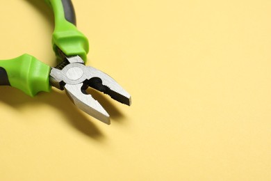 Photo of Combination pliers on yellow background, closeup. Space for text