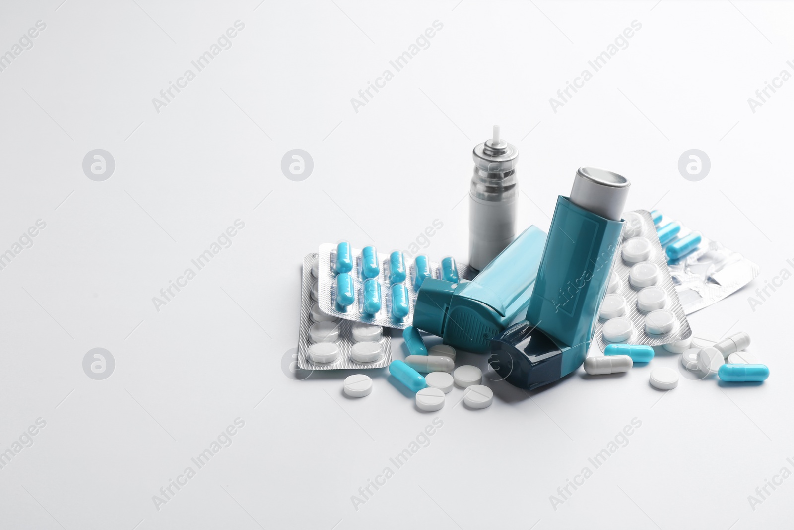 Photo of Asthma inhalers, pills and space for text on white background