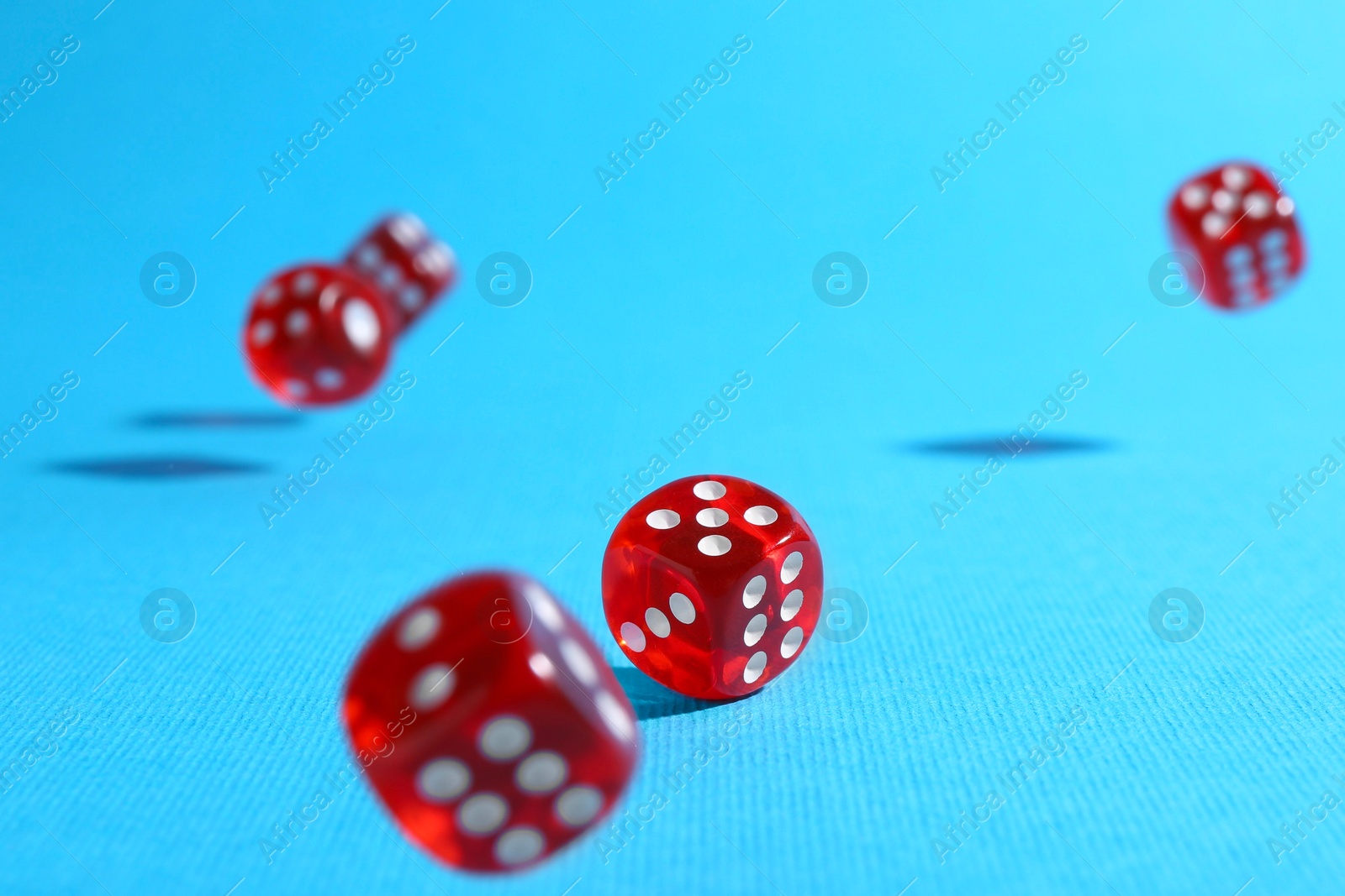 Photo of Many red game dices falling on light blue background