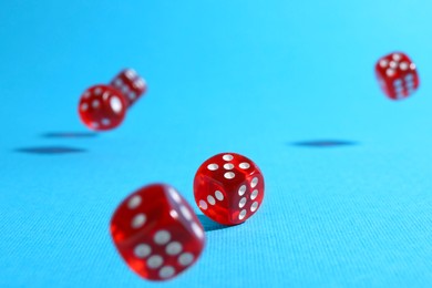 Many red game dices falling on light blue background