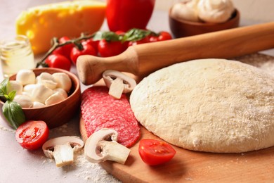 Photo of Pizza dough, products and rolling pin on gray table, closeup