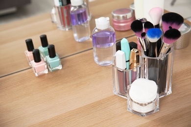 Organizer with makeup cosmetic products on wooden table near mirror