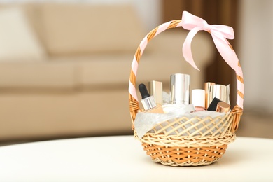 Photo of Wicker basket full of gifts on white table in living room. Space for text