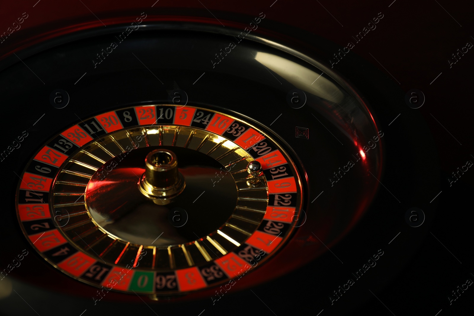 Photo of Roulette wheel with ball on black table, closeup. Casino game