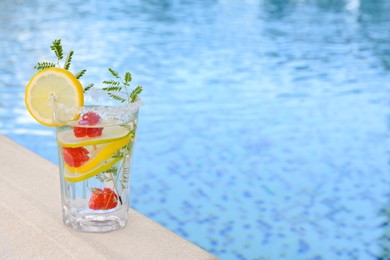 Photo of Delicious refreshing lemonade with raspberries near swimming pool, space for text