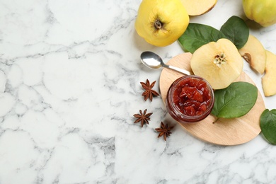 Photo of Delicious quince jam and fruits on white marble table, flat lay. Space for text