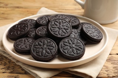 Photo of Plate with tasty sandwich cookies on wooden table, closeup