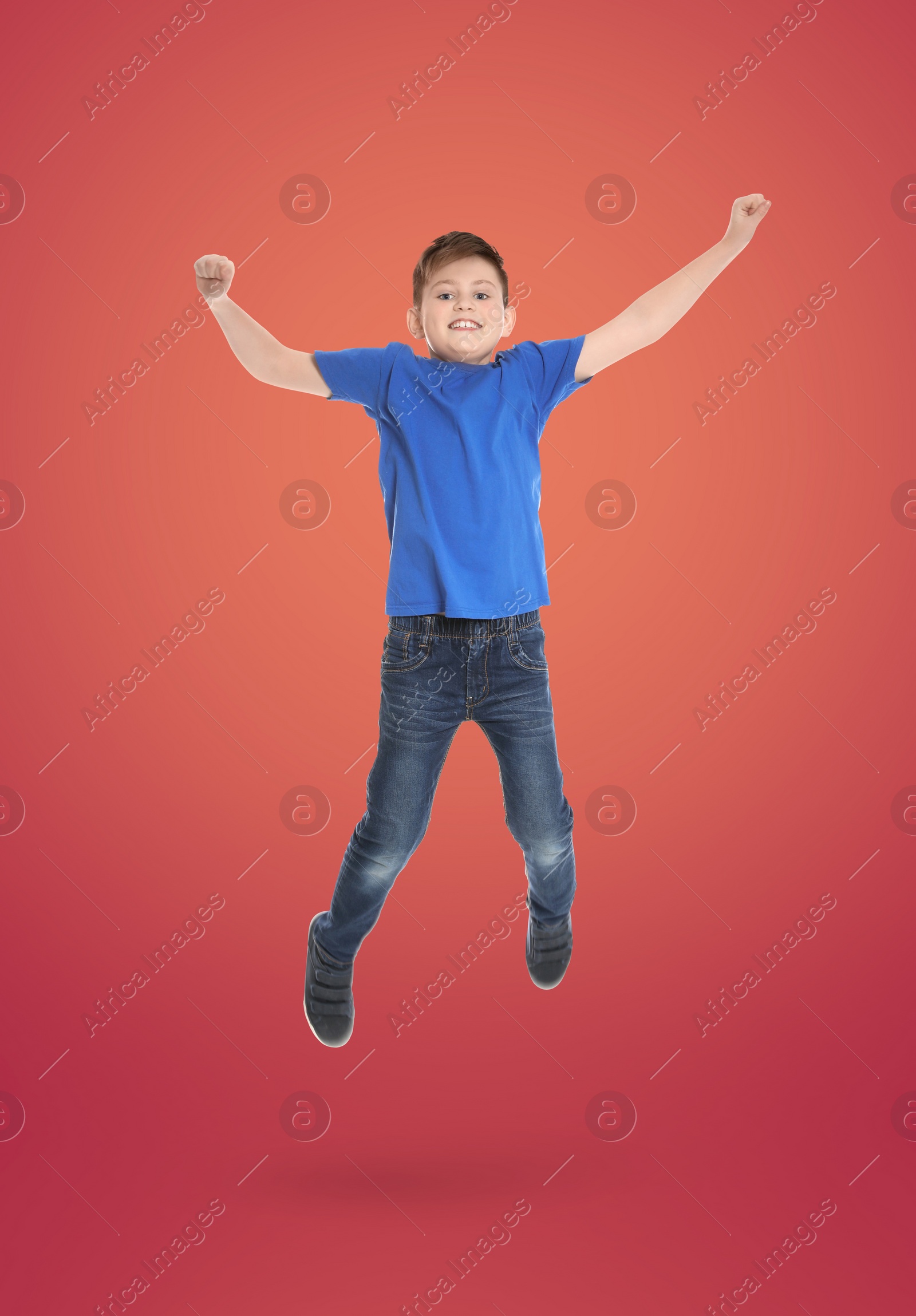 Image of Happy boy jumping on color gradient background