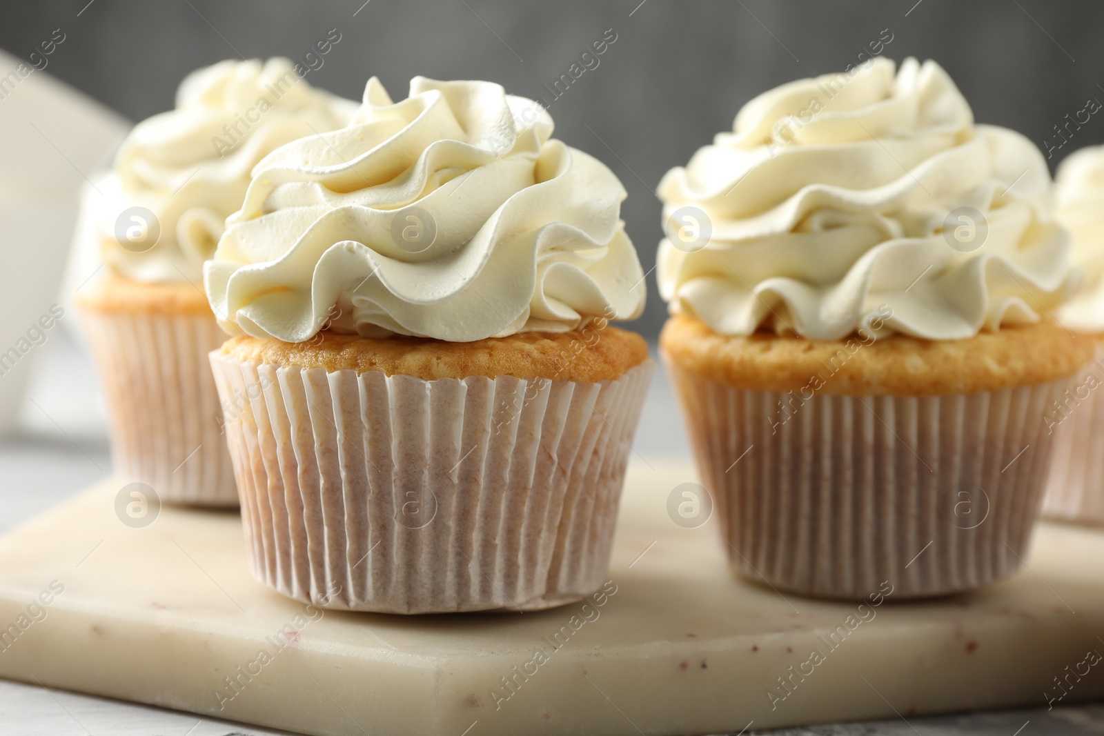 Photo of Tasty cupcakes with vanilla cream on table, closeup