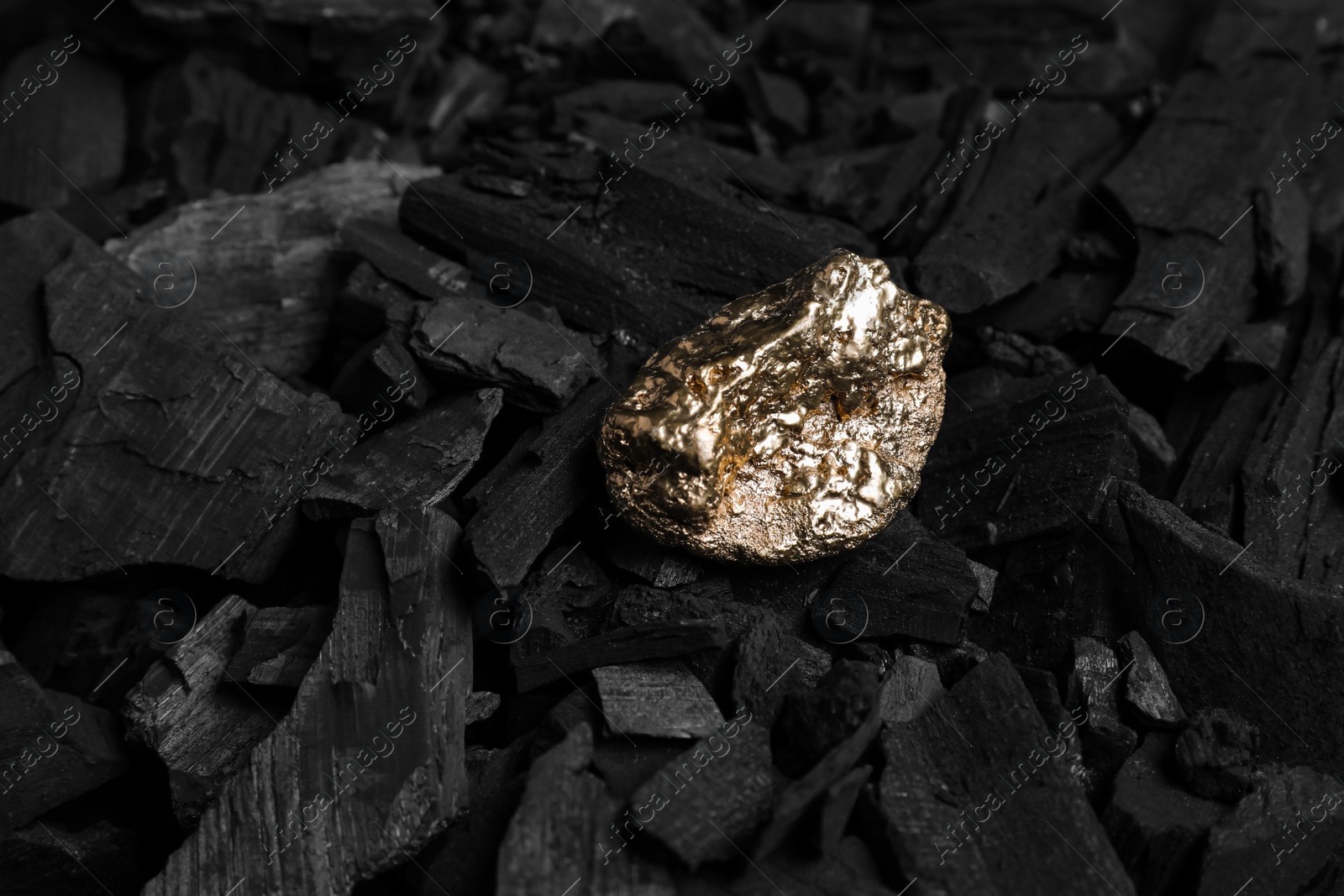 Photo of Shiny gold nugget on coals, closeup view