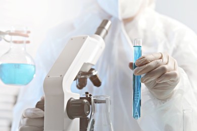 Image of Genetics research. Scientist holding test tube with liquid and illustration of DNA structure in laboratory, closeup
