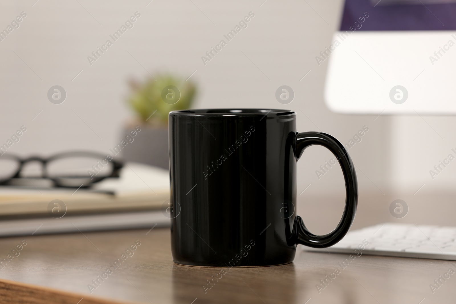 Photo of Black ceramic mug on wooden table at workplace