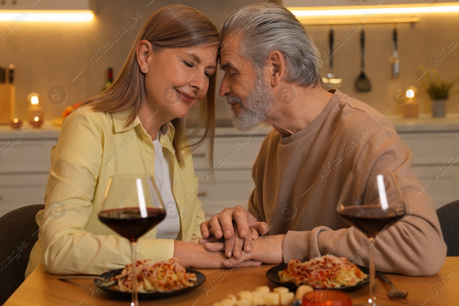 Photo of Affectionate senior couple having romantic dinner at home