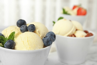 Photo of Delicious vanilla ice cream with blueberries served on table, closeup. Space for text