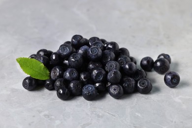 Photo of Ripe bilberries and leaf on grey marble table, closeup