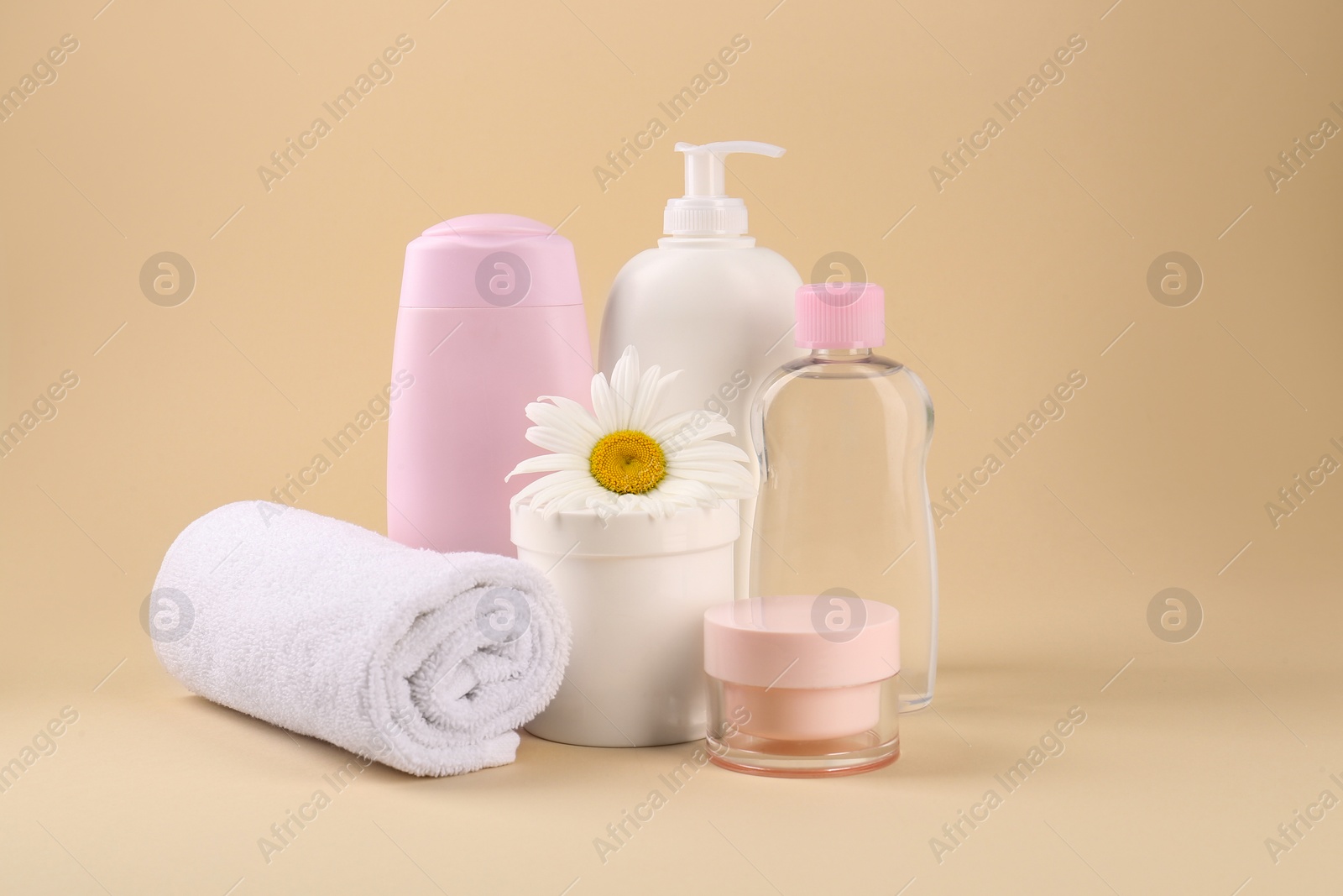 Photo of Different skin care products for baby, flower and towel on beige background