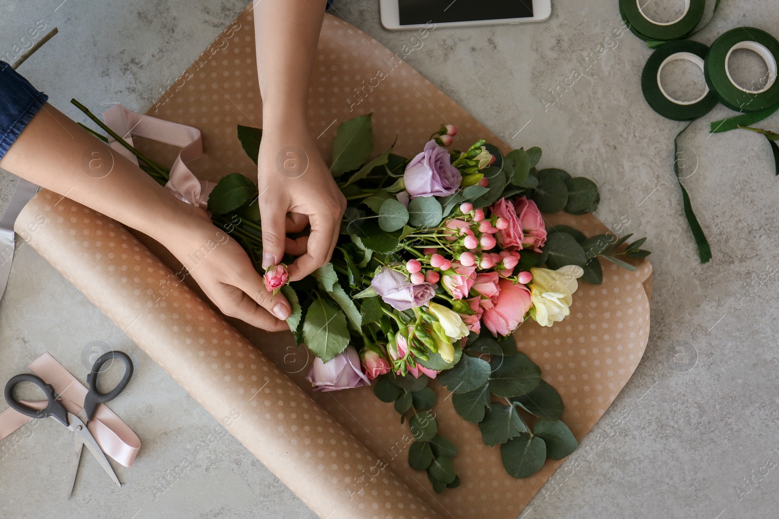 Photo of Female florist creating beautiful bouquet at table, top view