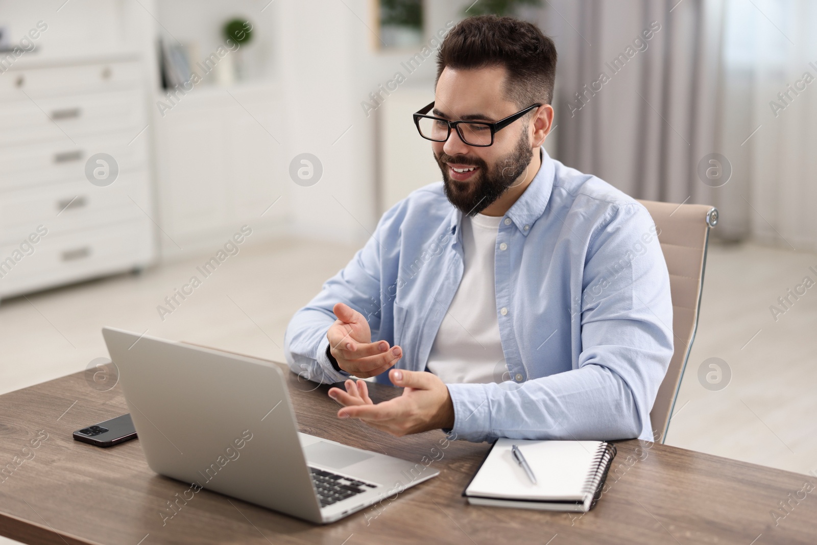 Photo of Young man using video chat during webinar at table in room