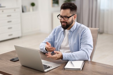 Young man using video chat during webinar at table in room