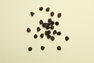 Delicious chocolate chips on beige background, top view