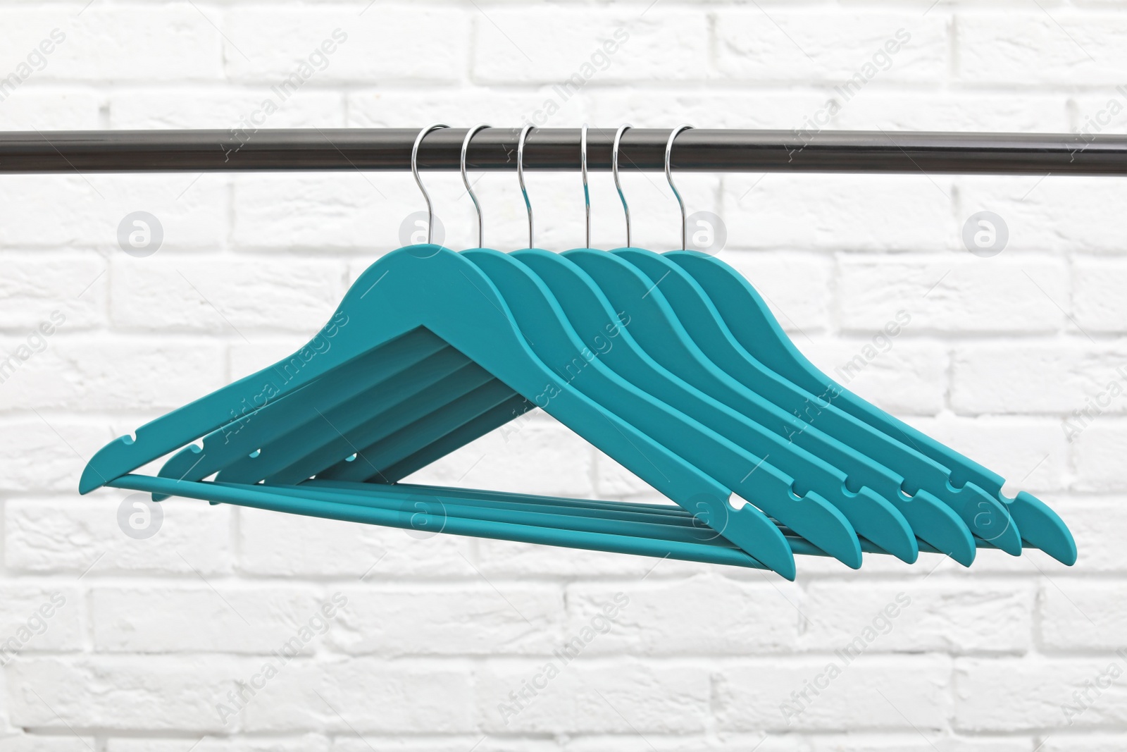 Photo of Clothes hangers on metal rail against brick wall background