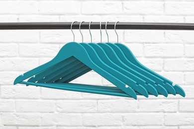 Photo of Clothes hangers on metal rail against brick wall background