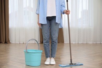 Woman with mop and bucket indoors, closeup. Cleaning service