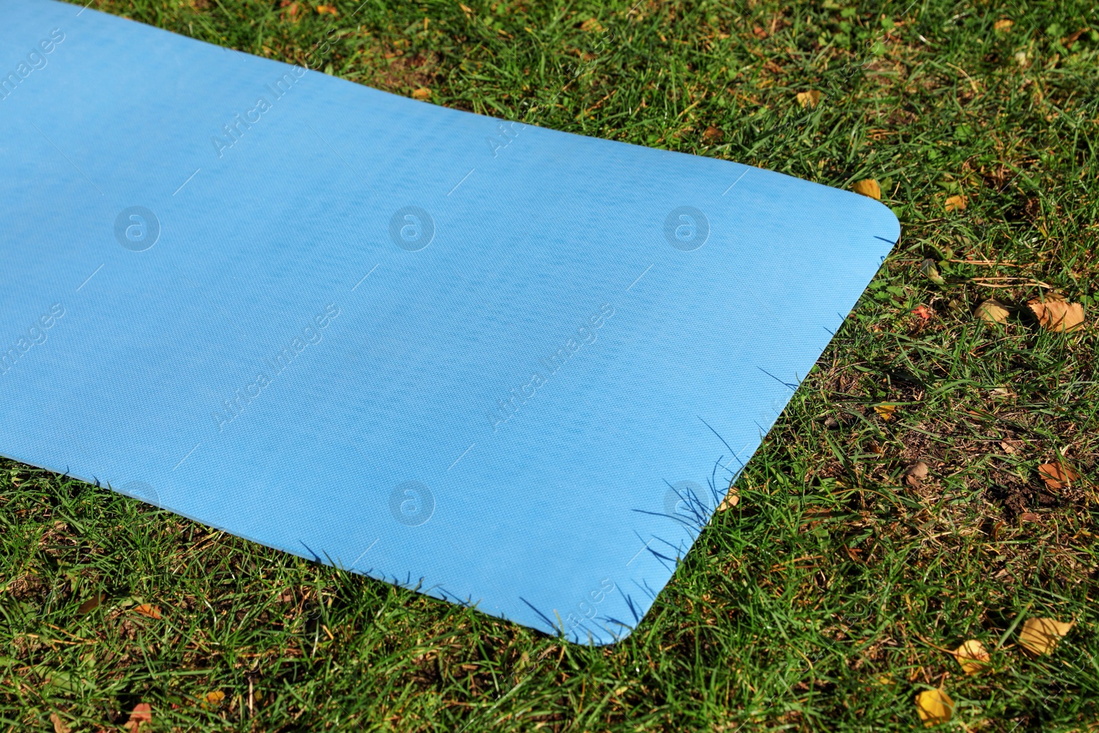 Photo of Blue karemat or fitness mat on fresh green grass outdoors