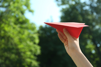 Woman holding paper plane outdoors, closeup. Space for text