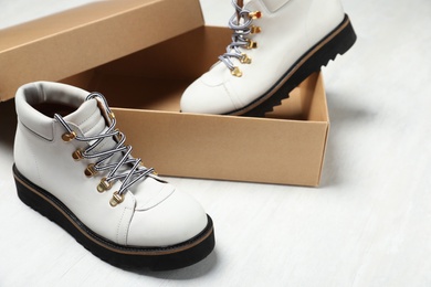 Pair of stylish boots and box on white wooden background. Space for text