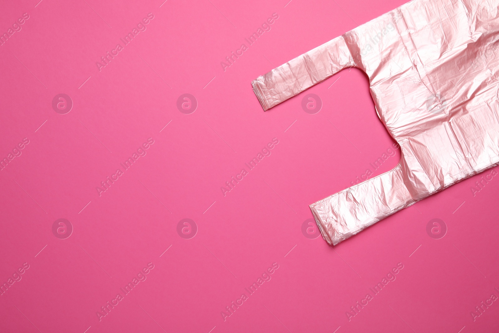 Photo of Pack of plastic bags on pink background, top view. Space for text