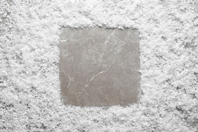 Frame made of snow on marble background, top view with space for text. Winter season