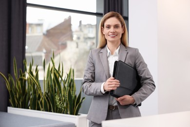 Happy real estate agent with leather portfolio indoors