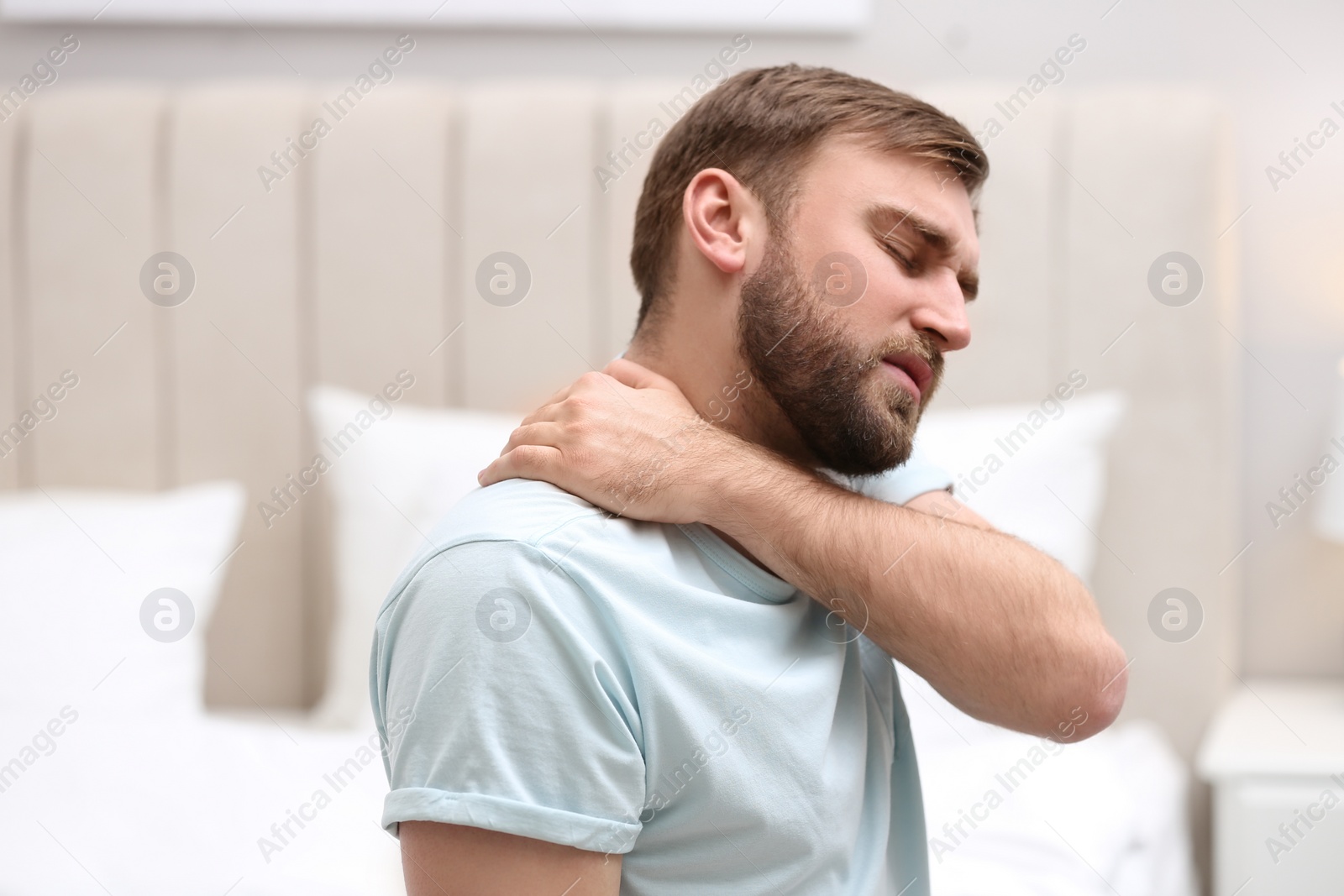 Photo of Man suffering from neck pain at home. Bad posture problem