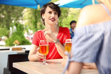 Young women with glasses of cold beer at table