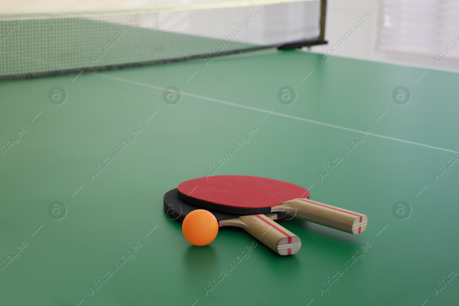 Photo of Rackets and ball on ping pong table, space for text