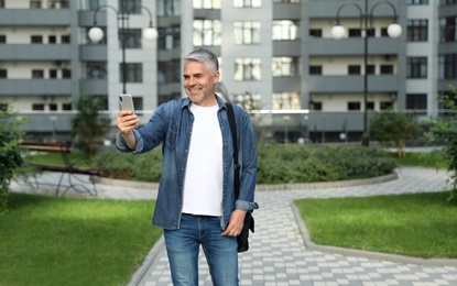 Photo of Handsome mature man taking selfie in city center. Space for text