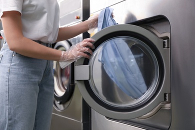 Photo of Young woman unloading washing machine in dry-cleaning, closeup
