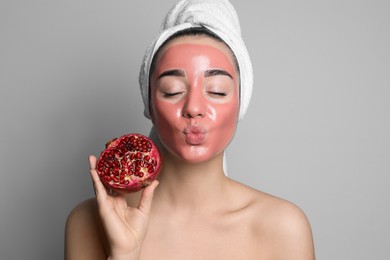 Photo of Woman with pomegranate face mask and fresh fruit on grey background