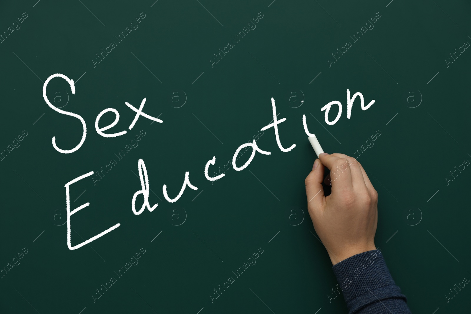 Image of Man writing words Sex Education on green chalkboard, closeup