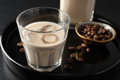 Coffee cream liqueur in glass and beans on table, closeup