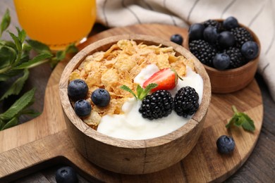 Photo of Delicious crispy cornflakes, yogurt and fresh berries in bowl on wooden table, closeup. Healthy breakfast