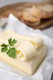 Photo of Tasty butter with curl and parsley on table, closeup