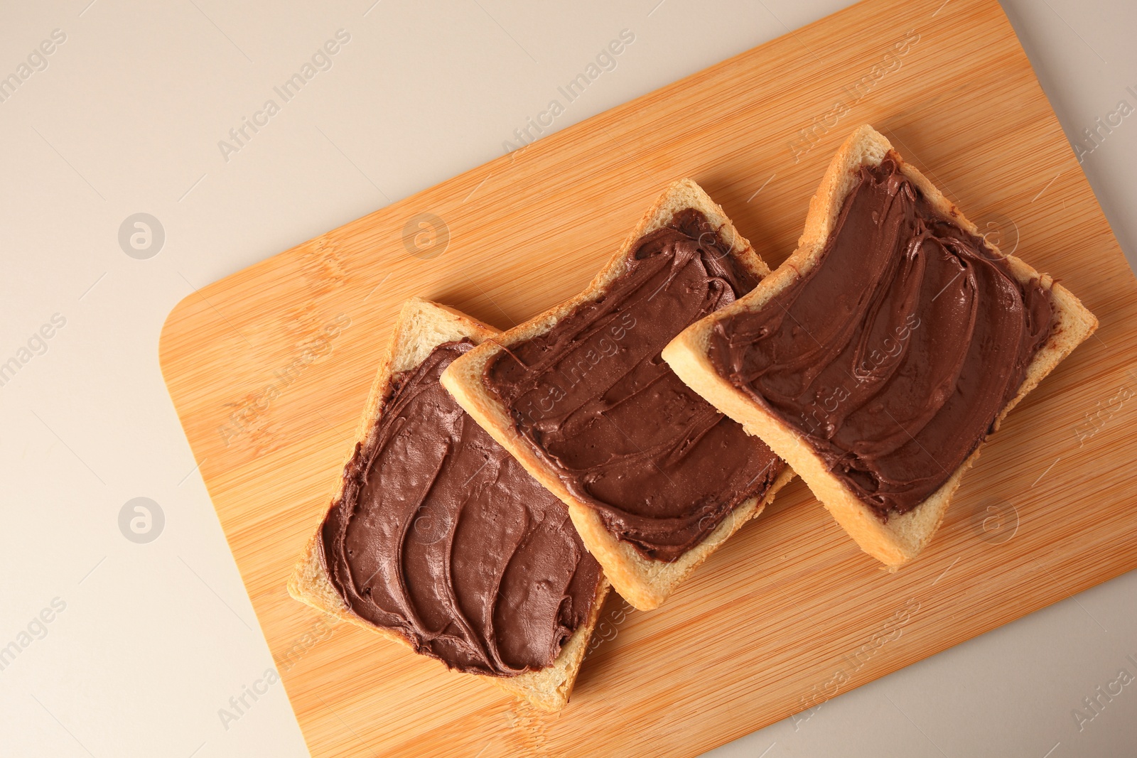 Photo of Tasty toasts with chocolate paste on beige background, top view