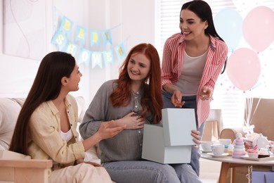 Happy pregnant woman spending time with friends at baby shower party