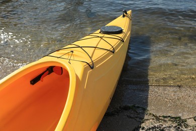 Photo of Yellow kayak on beach near river, closeup. Summer camp activity