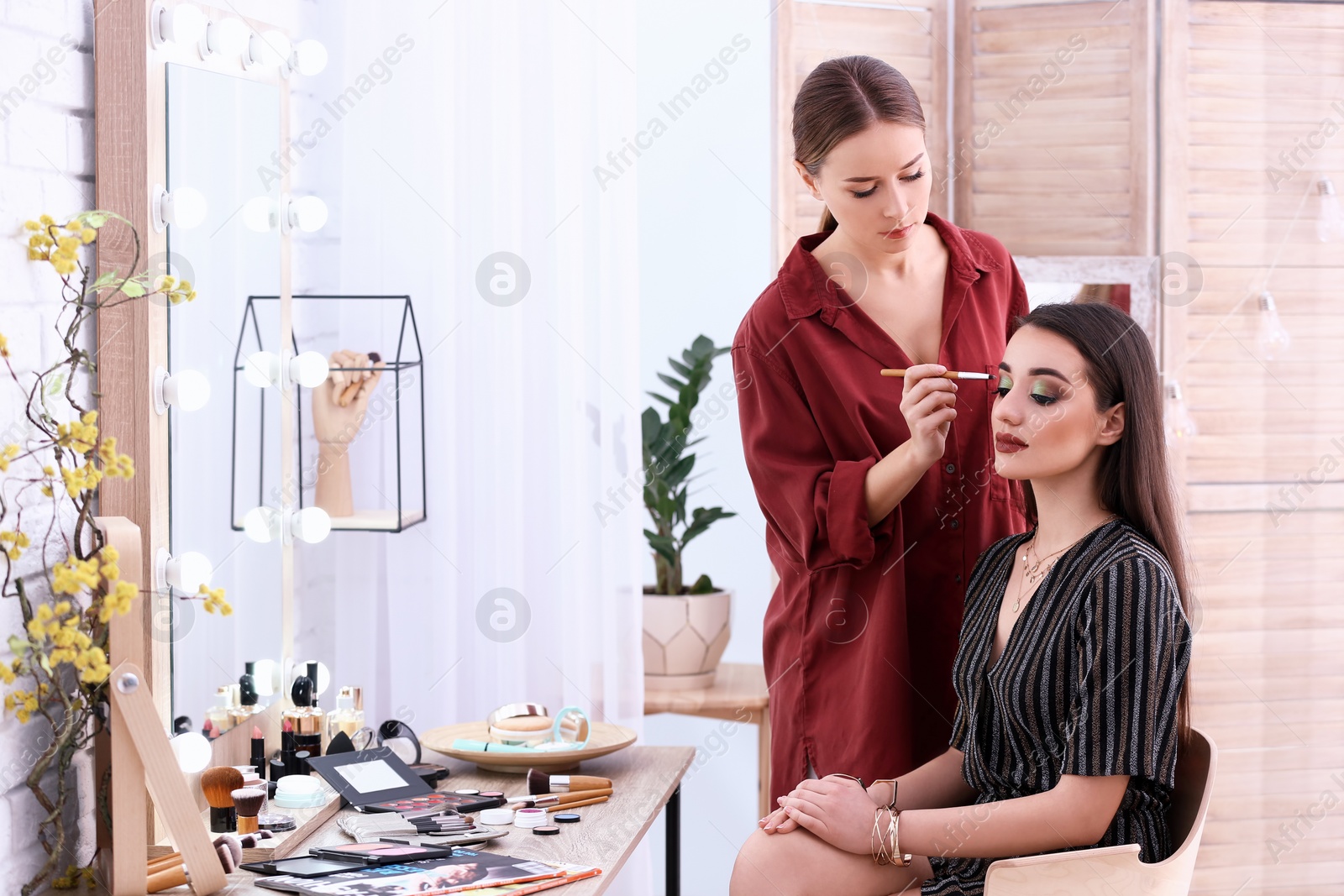 Photo of Professional visage artist applying makeup on woman's face in salon