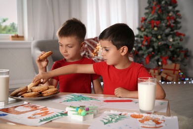 Photo of Little children eating cookies at home. Christmas celebration