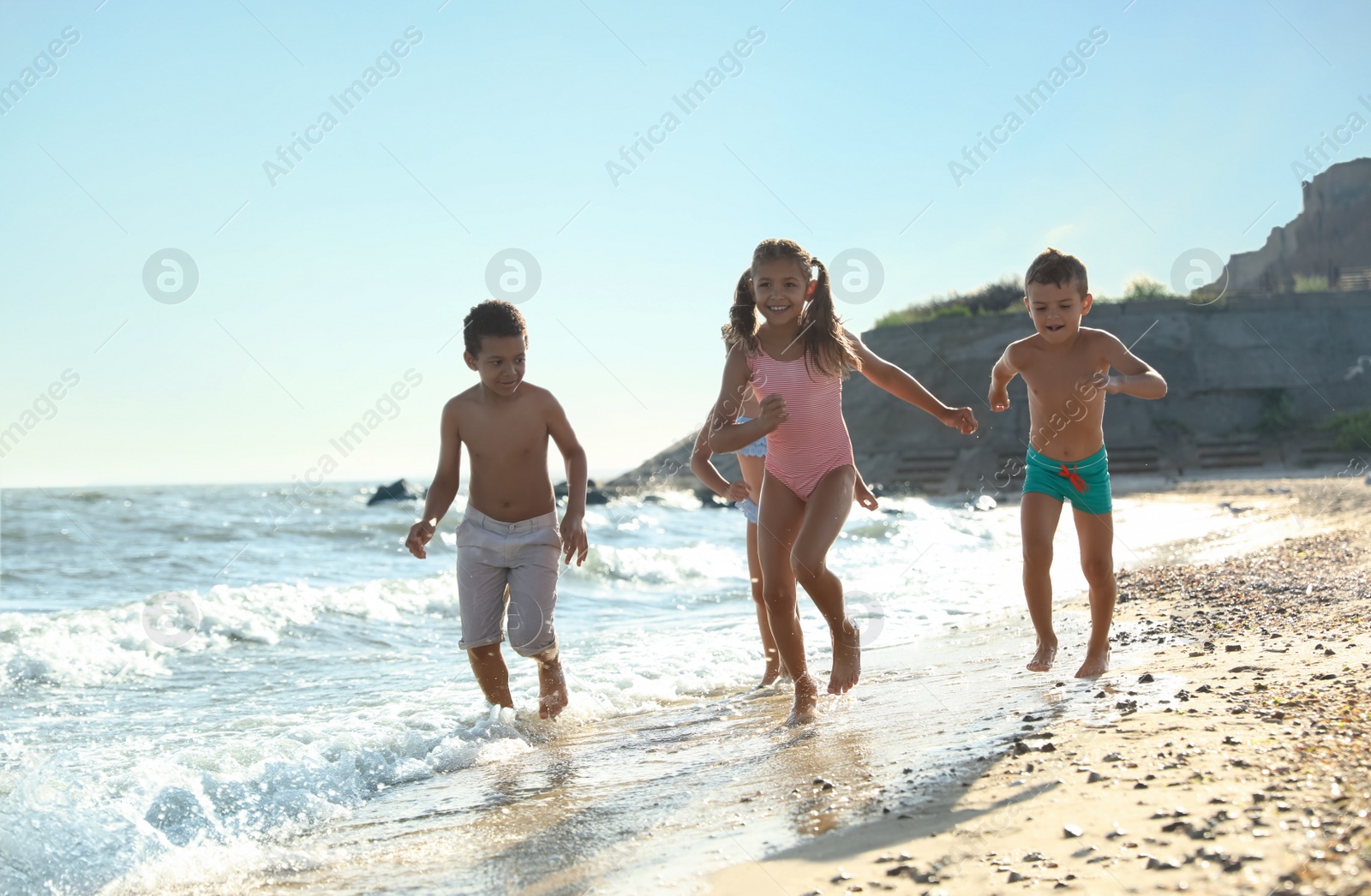 Photo of Cute children enjoying sunny day at beach. Summer camp