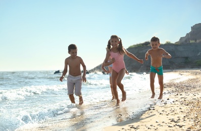 Photo of Cute children enjoying sunny day at beach. Summer camp